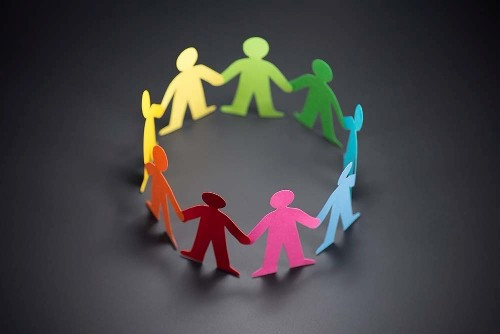 Photo of multicoloured paper cut out of people in a circle holding hands